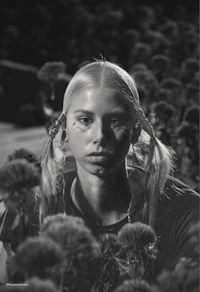 a black and white photo of a girl in a field of flowers