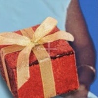a woman holding a red gift box with a gold ribbon