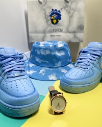 a pair of blue nike air force 1 sneakers, a hat and a watch