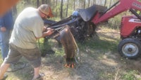 a man working on a tractor in the woods