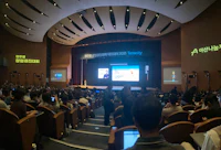 a large auditorium filled with people watching a presentation