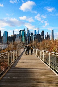 people walking on a wooden boardwalk in front of a city skyline