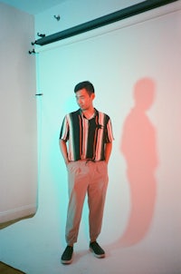 a man in a striped shirt standing in front of a studio