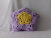 a crocheted star shaped pillow in purple and yellow