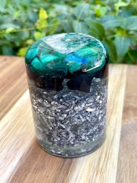 a glass jar filled with black and green stones