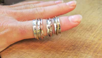 a person's hand holding a stack of rings on a wooden table
