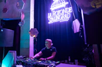 a dj in front of a large neon sign