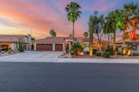 a home with palm trees and a driveway at sunset