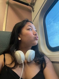 a woman wearing headphones looking out the window of a train