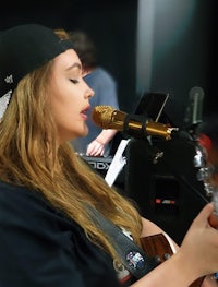 a woman singing into a microphone while playing an acoustic guitar