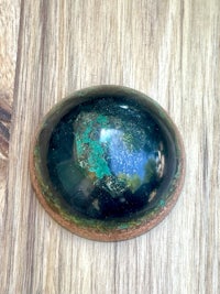 a green and brown stone on a wooden surface
