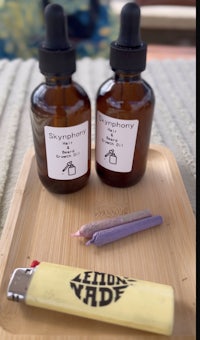 two bottles of cbd oil and a lighter on a tray