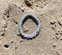 a bracelet with the word laugh in the sand