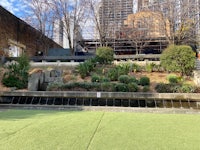 a green grassy area with a fountain in the middle
