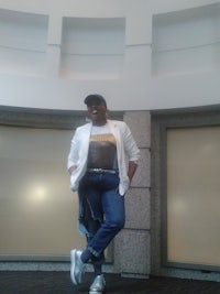 a woman in a white blazer and jeans posing for a photo