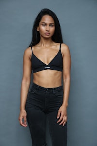 a woman in a black bra top posing on a blue background