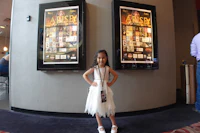 a little girl in a white dress standing in front of movie posters