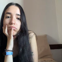 a woman sitting on a bed with her hand on her chin
