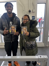 two people standing next to each other holding cds