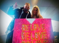 a man and woman holding a sign that says believe love believe