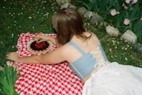 a woman laying on a blanket eating a pie