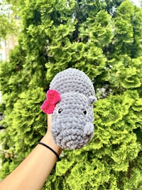 a person holding a crocheted hippo