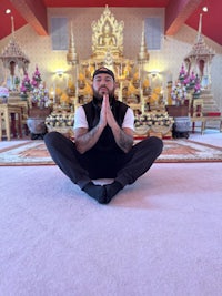 a man sitting on the floor in front of a buddhist temple