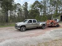 a truck is being pulled by a bulldozer in a wooded area