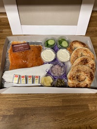 a box containing salmon, bagel and dip