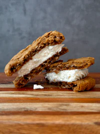 two cookies and cream sandwiches on a wooden cutting board