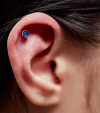 a woman's ear with a blue sapphire piercing