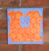 an orange and blue piece of art on a brick wall