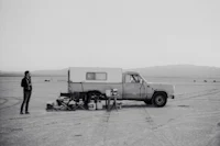 a man standing next to a camper in the desert