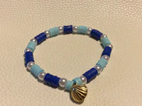 a blue and white bracelet with a shell charm