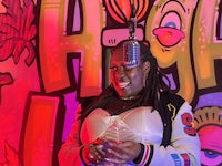 a woman with dreadlocks and a microphone in front of a graffiti wall