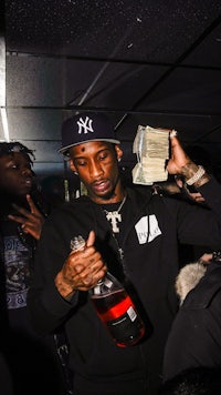 a man holding a bottle of money in front of a crowd