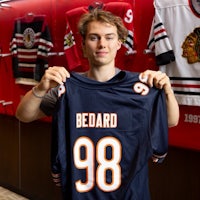 a young man holding up a chicago blackhawks jersey