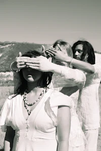 a black and white photo of a group of people covering their eyes