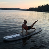 a woman doing a yoga pose on a stand up paddle board