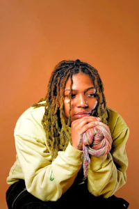 a young man with dreadlocks and a sweater