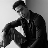a black and white photo of a man leaning against a wall