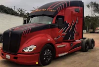 a red and black semi truck parked in a dirt lot
