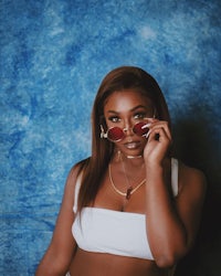 a woman in a white top and red sunglasses posing for a photo