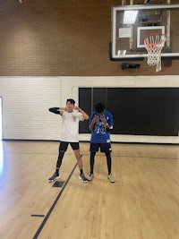 two people playing basketball on a gym floor