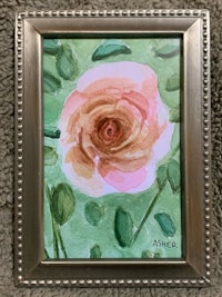 a watercolor painting of a rose in a silver frame