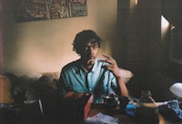 a man sitting at a table and smoking a cigarette