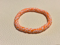 an orange and white stretch bracelet on a table