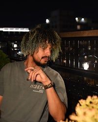 a man with dreadlocks sitting on a balcony