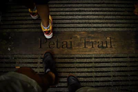 two people standing next to a wooden sign that says petai trail