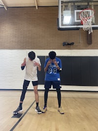 two people standing on a basketball court
